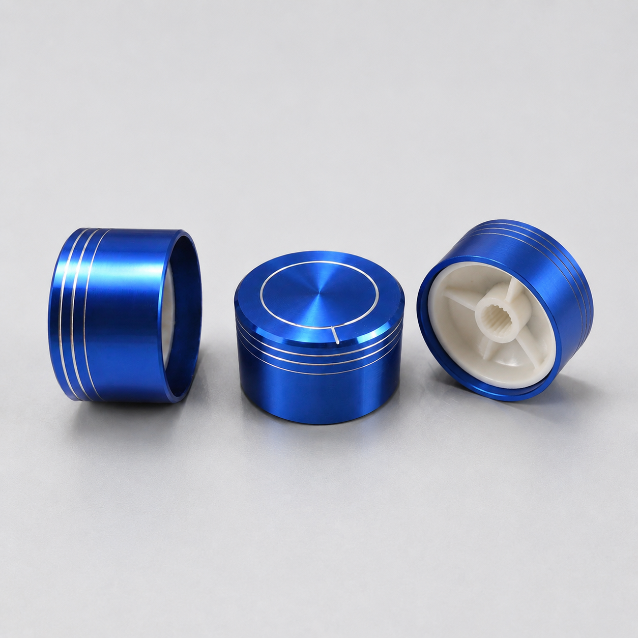 Studio composition of three blue control knobs showing the face, side and white internal fitting